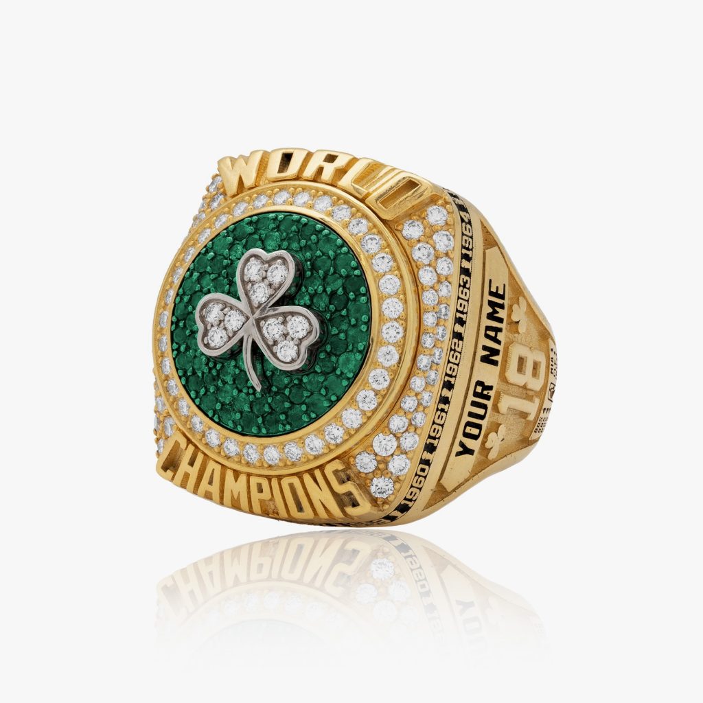 Gold championship ring featuring a green and white shamrock design, surrounded by diamonds and engraved details.