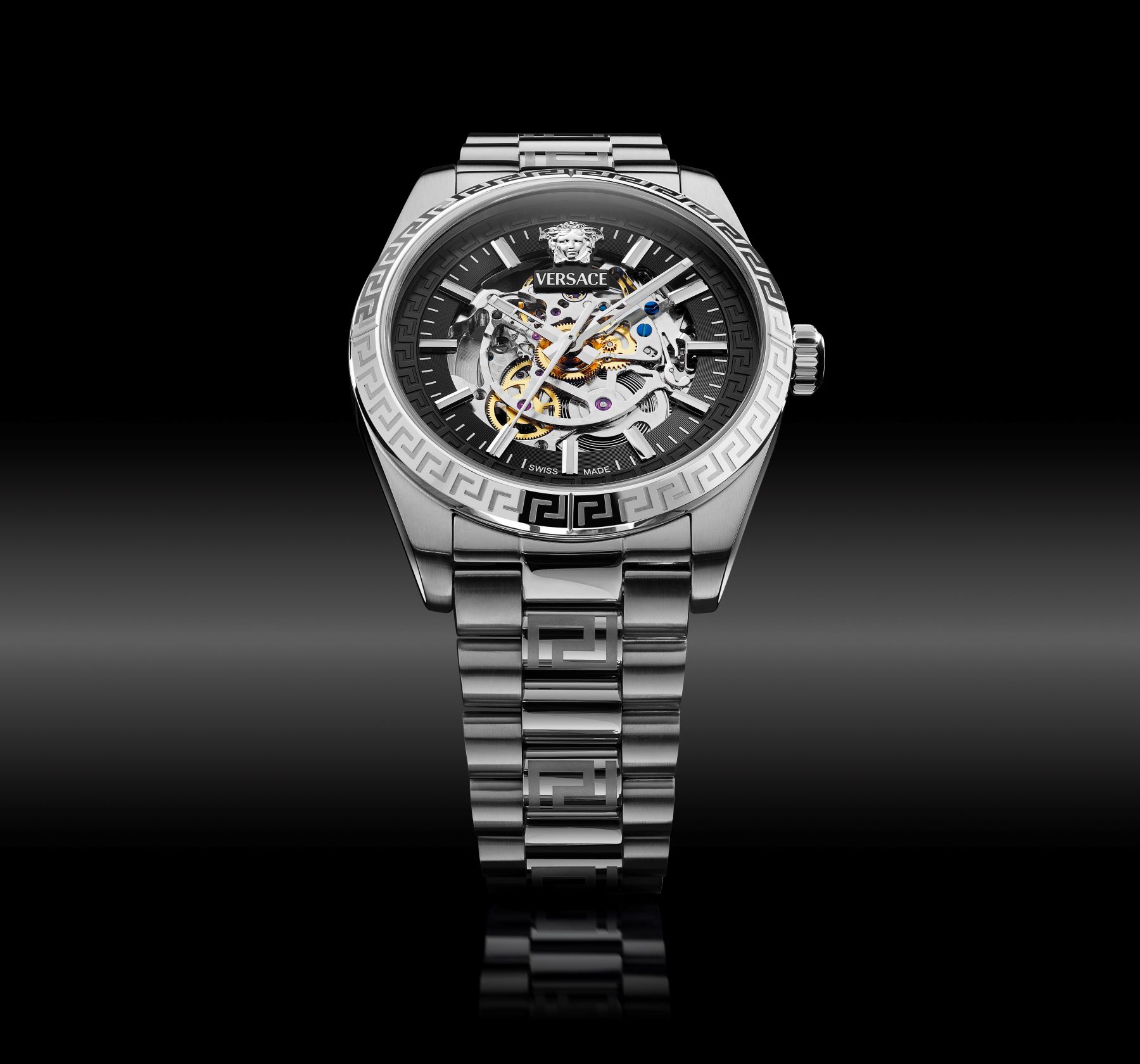 Versace automatic watch with a skeleton dial and metallic bracelet, featuring a Greek key design on the case.